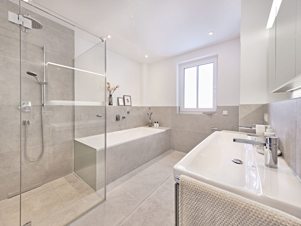 Badezimmer mit Regendusche und Badewanne eines Neubau Mehrfamilienhauses mit fünf Wohnungen und Tiefgarage von DOMINO Bau in der Thaddäus-Eck-Straße in München-Obermenzing