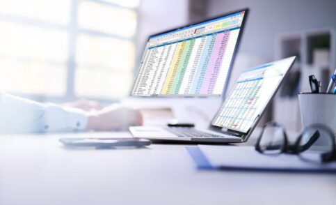 Zwei Monitore mit Excel-Dateien und Zahlen, Renditeberechnungen