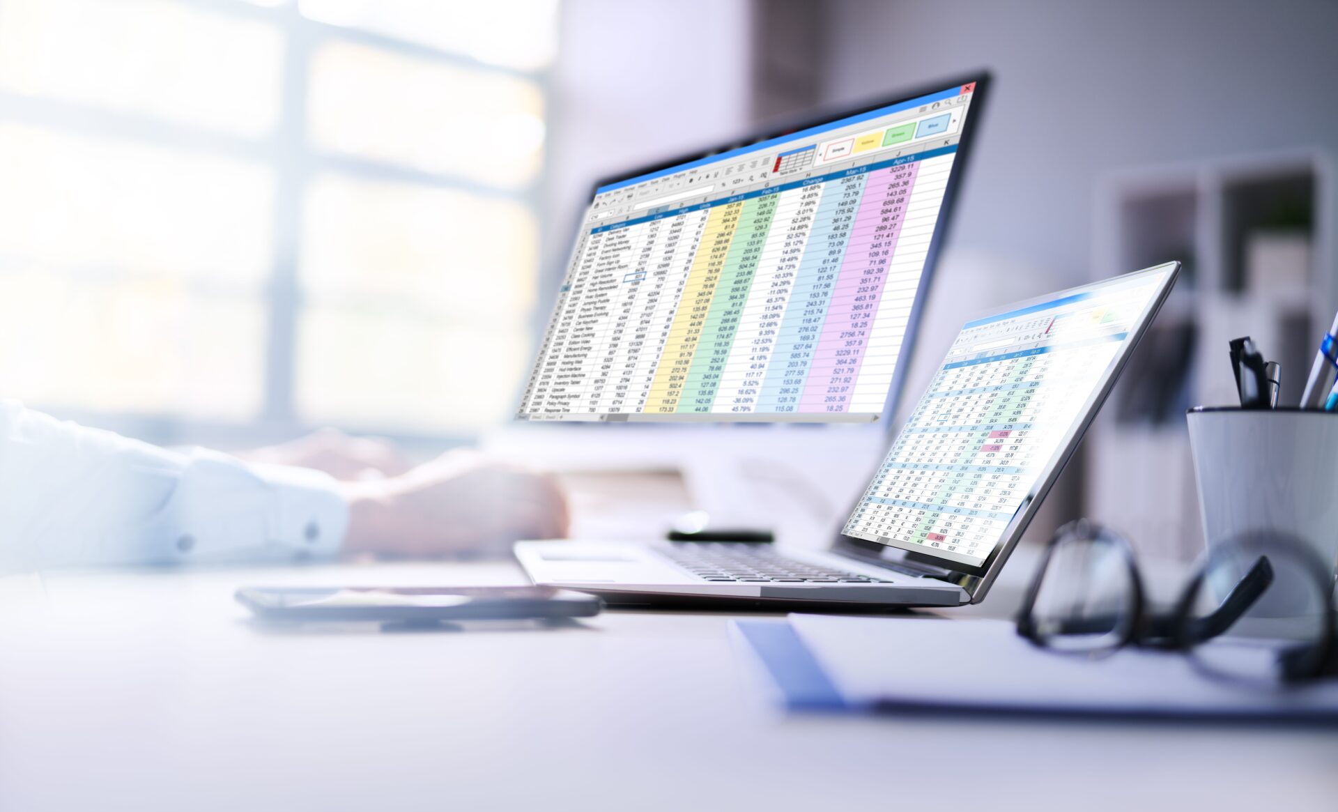 Zwei Monitore mit Excel-Dateien und Zahlen, Renditeberechnungen