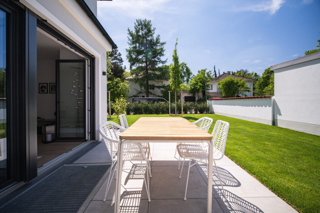 Terrasse und Garten mit Blick ins Wohnzimmer; Neubau Doppelhaus von DOMINO Bau in München Obermenzing