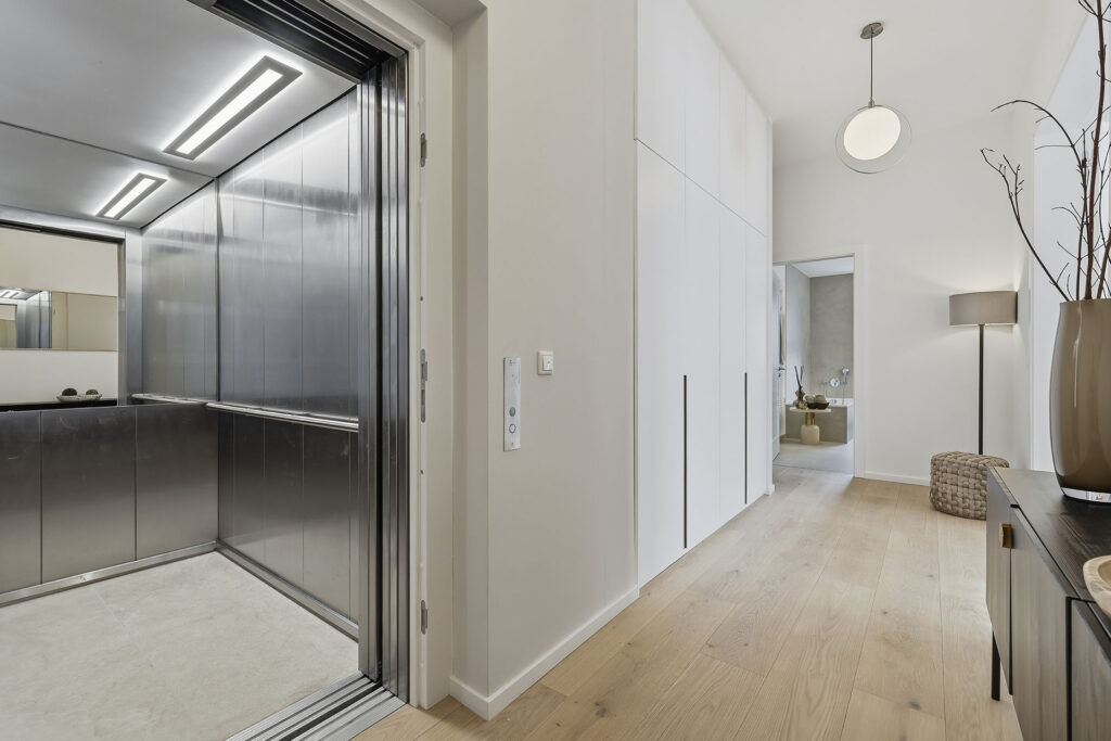Photo of an elevator with direct access to the hallway in the attic of a three-unit apartment building by DOMINO Bau in Munich Solln