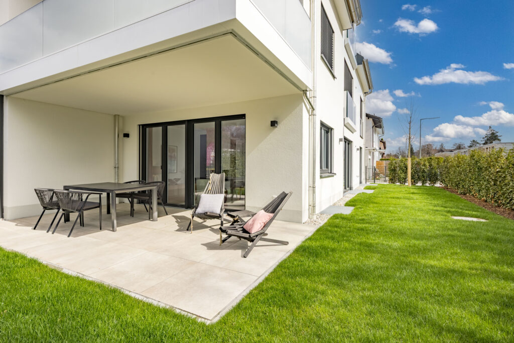 Foto einer Terrasse mit Garten im Erdgeschoss, Neubau Mehrfamilienhaus mit drei Wohnungen von DOMINO Bau in München Solln
